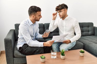 Two hispanic men business workers reading document working at office