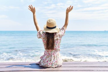 Plajda bankta oturan, yaz şapkası takan genç Latin kız..