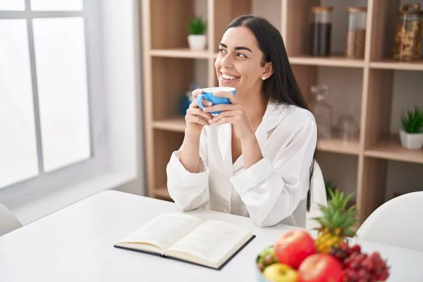 Young Hispanic Woman Reading Book Drinking Coffee Home — Stockfoto