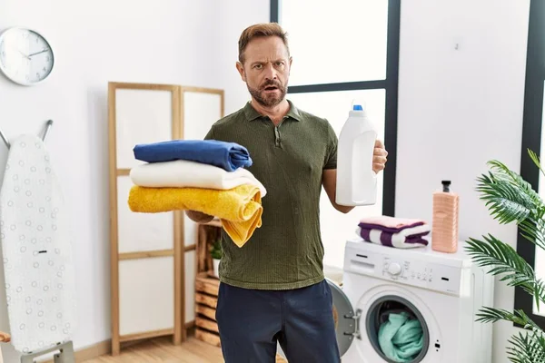 Middle Age Man Holding Clean Laundry Detergent Bottle Shock Face — Stockfoto