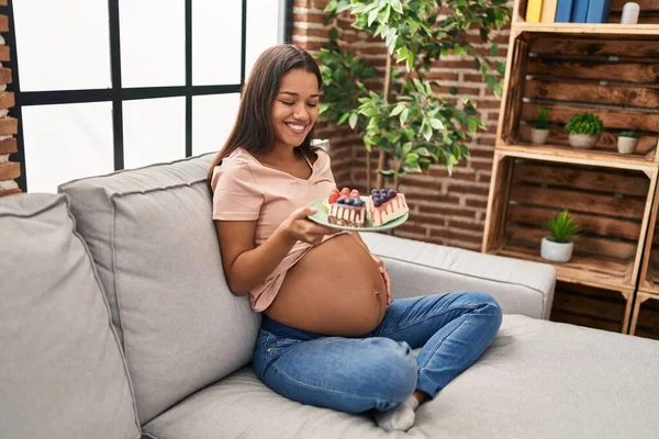 Young Latin Woman Pregnant Eating Sweets Sitting Sofa Home — Foto de Stock