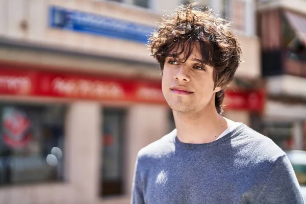 Young hispanic man with relaxed expression standing at street