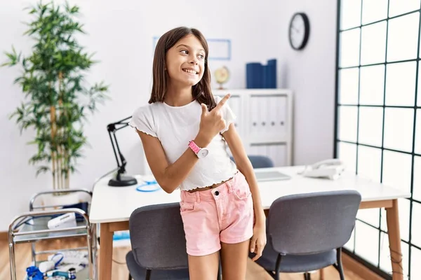 Young Hispanic Girl Standing Pediatrician Clinic Cheerful Smile Face Pointing — Stok fotoğraf