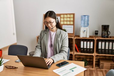 Ofiste çalışırken gülümseyen Çinli bir çağrı merkezi ajanı..