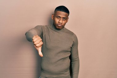 Balıkçı yaka kazak giyen genç siyahi adam mutsuz ve kızgın görünüyor. Reddedilmiş ve olumsuz. kötü ifade. 