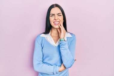Pembe arka planda duran mavi gözlü güzel bir kadın diş ağrısı ya da diş hastalığından dolayı acı dolu bir ifadeyle dudaklarına dokunuyor. dişçi 
