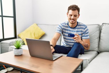 Genç İspanyol adam evde kredi kartı tutuyor.