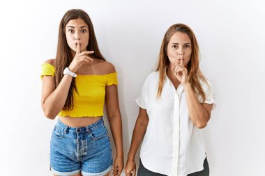 Anne ve kızı birlikte izole edilmiş arka planda durarak parmakları dudaklarında sessiz olmak istiyorlar. sessizlik ve gizli konsept. 