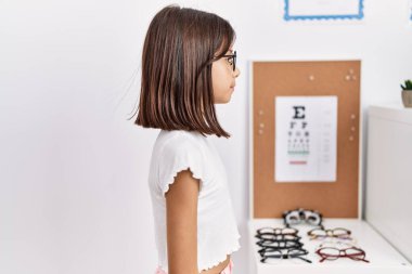 Young hispanic girl wearing glasses looking to side, relax profile pose with natural face with confident smile. 