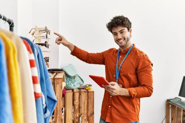 Elbise mağazasında çalışan dokunmatik ped kullanan, mutlu gülümseyen bir İspanyol esnaf..