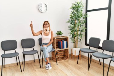 Kafkasyalı yaralı genç kız gülümsüyor. Yaka takıyor, doktor bekleme odasında oturuyor..