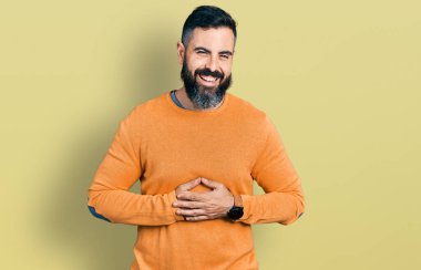 Sakallı, sıradan bir kazak giyen, gülen ve gülen İspanyol bir adam.. 