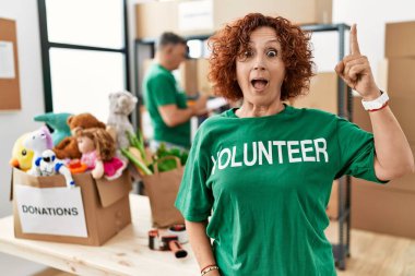 Bağışlarda gönüllü tişört giyen orta yaşlı bir kadın başarılı bir fikri işaret ediyor. Heyecanlı ve mutlu. Bir numara.. 