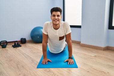 Genç İspanyol adam gülümsüyor spor merkezinde esniyor.