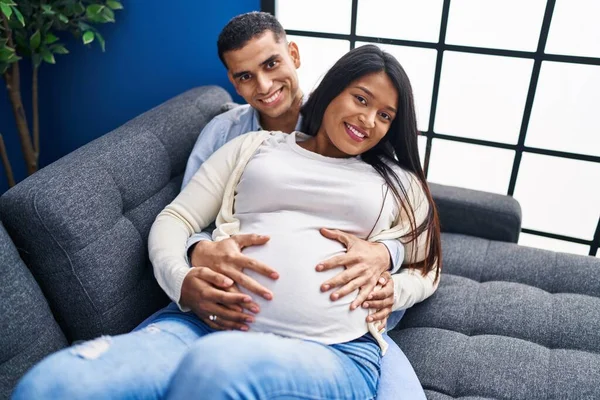 Young Latin Couple Expecting Baby Touching Belly Lying Sofa Home — Fotografia de Stock