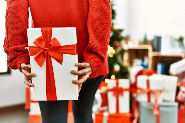 Young Hispanic Woman Holding Gift Back Standing Christmas Tree Home — Stock Photo, Image