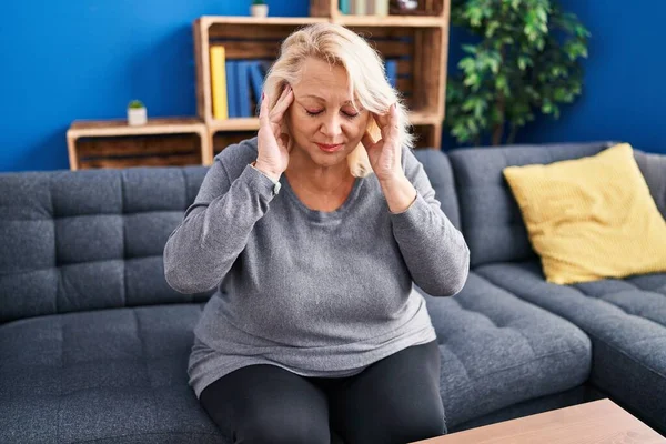 Middle age blonde woman suffering for headache at home