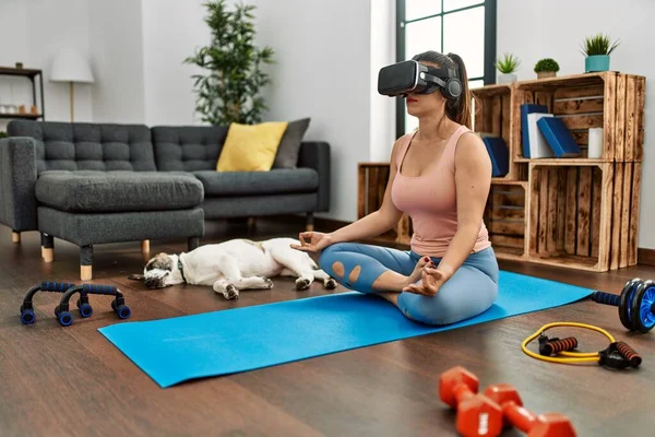 Young woman having online yoga class using vr goggles at home