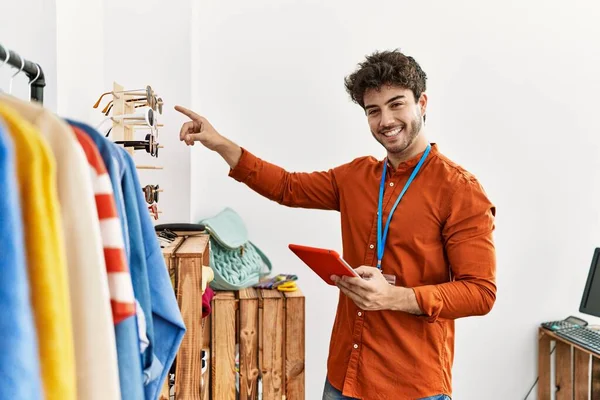 Elbise mağazasında çalışan dokunmatik ped kullanan, mutlu gülümseyen bir İspanyol esnaf..