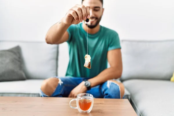 Młody Arabski Człowiek Uśmiecha Się Pewnie Trzymając Torebkę Herbaty Domu — Zdjęcie stockowe