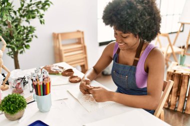 Genç afro-amerikan kadın gülümsüyor sanat stüdyosunda kil manipülasyonu yapıyor