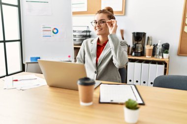 Ofiste çalışan genç bir iş kadını dizüstü bilgisayar kullanıyor.