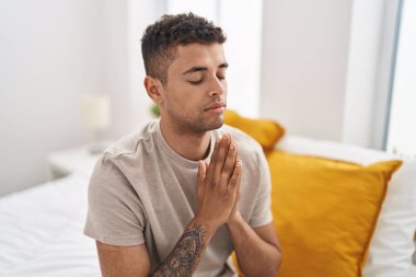 Afro-Amerikalı bir adam yatakta dua ediyor.