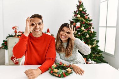 Genç İspanyol çift Noel 'de masada oturuyor. El hareketleriyle gülümsüyor, gözleri mutlu yüzleriyle parmaklarının arasından bakıyor.. 