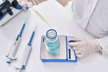 Genç kadın bilim adamı laboratuvarda sıvı tartıyor.