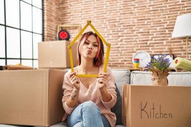 Yeni evindeki kanepede oturan beyaz bir kadın kameraya bakıp öpüşürken çok güzel ve seksi oluyor. aşk ifadesi. 