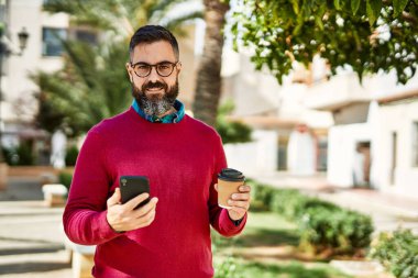 Genç İspanyol yönetici akıllı telefon kullanıyor ve şehirde kahve içiyor..