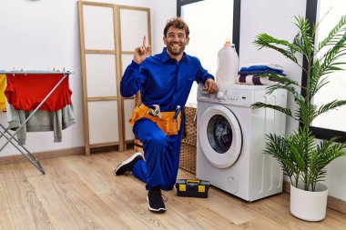 Çamaşır makinesinde çalışan genç İspanyol bir adam bir fikre ya da soru işaretine şaşırdı ve mutlu bir yüzle işaret etti. 