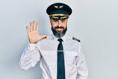 İspanyol asıllı genç adam uçak pilotu üniforması giyiyor. Beş numaralı parmaklarıyla işaret ediyor ve gülümsüyor. Kendinden emin ve mutlu.. 
