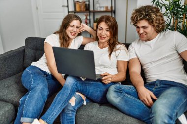 Anne ve çift evdeki koltukta dizüstü bilgisayar kullanıyor.