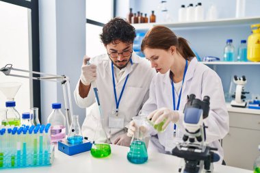 Erkek ve kadın bilim adamları laboratuarda çalışıyor.