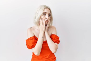 Kafkasyalı genç bir kadın izole arka planda duruyor. Yüzü, depresyonu ve üzüntüyü örten yorgun eller, sorun yüzünden üzgün ve sinirli. 