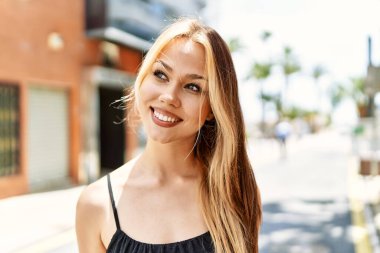 Genç beyaz kız gülümseyerek şehirde mutlu mesut duruyor..