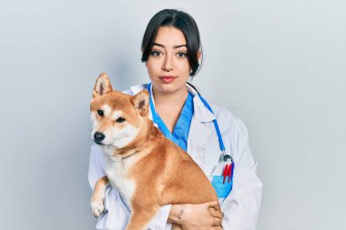 Yüzünde ciddi bir ifadeyle köpeği tutan güzel İspanyol veteriner kadın. Basit ve doğal bir şekilde kameraya bakıyorsun.. 