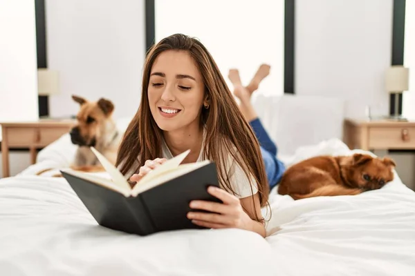 Young Hispanic Woman Reading Book Lying Bed Dogs Bedroom — Fotografia de Stock