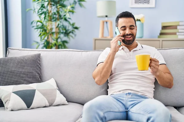 Hombre Hispano Joven Bebiendo Café Hablando Teléfono Inteligente Casa —  Fotos de Stock