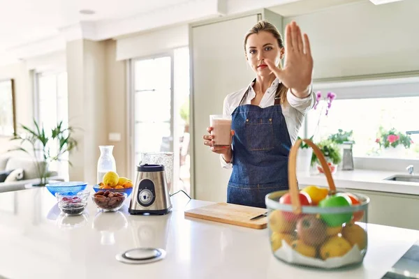 Beautiful Blonde Woman Wearing Apron Drinking Smoothie Kitchen Open Hand — Stok fotoğraf