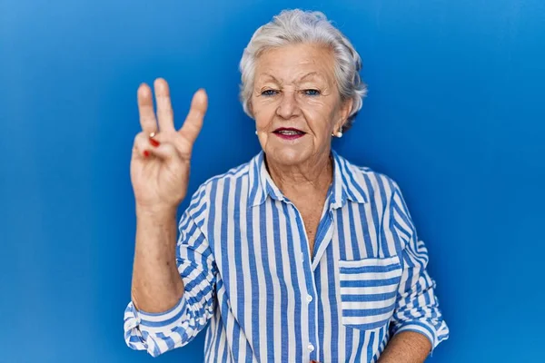 Старшая Женщина Седыми Волосами Стоящая Синем Фоне Показывающая Пальцами Номер — стоковое фото
