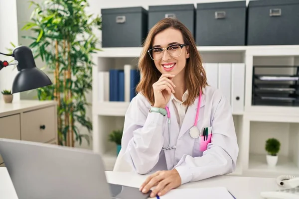 Klinikte çalışan doktor üniforması giyen genç bir kadın.