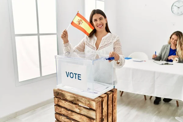 Young spanish voter woman smiling happy holding spain flag at electoral college.