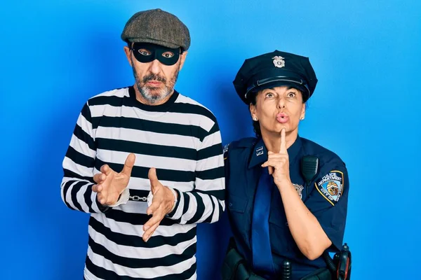 Middle age couple of hispanic woman and man wearing thief and police uniform thinking concentrated about doubt with finger on chin and looking up wondering