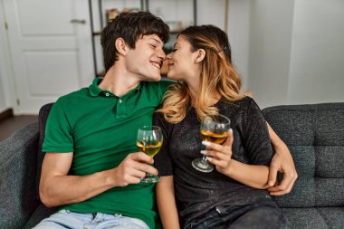 Genç beyaz çift mutlu bir şekilde gülümsüyor evde şampanya içiyorlar..