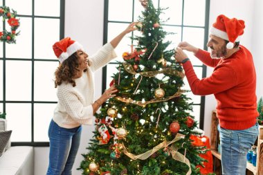 Orta yaşlı İspanyol çift gülümsüyor. Mutlu noel ağacı süslüyor evde..