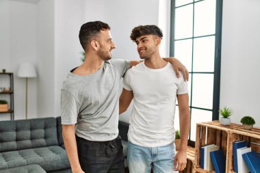 İki İspanyol erkek gülümsüyor. Evde birbirlerine sarılıyorlar.