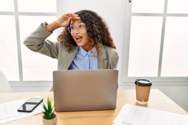 Güzel bir İspanyol iş kadını ofisinde oturmuş dizüstü bilgisayarla çalışıyor çok mutlu ve gülümsüyor başlarını kaldırıp uzaklara bakıyor. arama kavramı. 