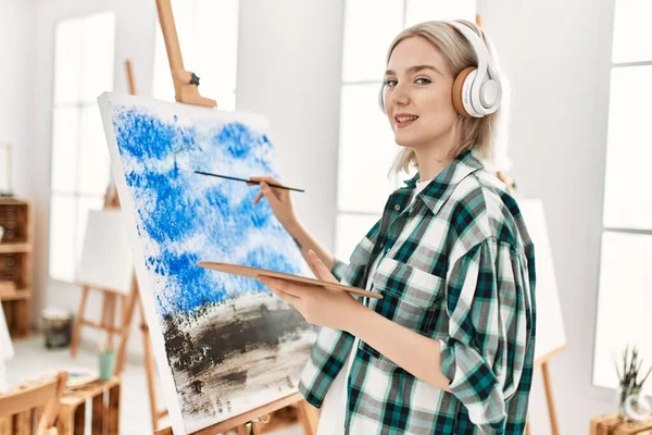 在艺术演播室里 年轻的女艺术家微笑着快乐的绘画和听着音乐 — 图库照片